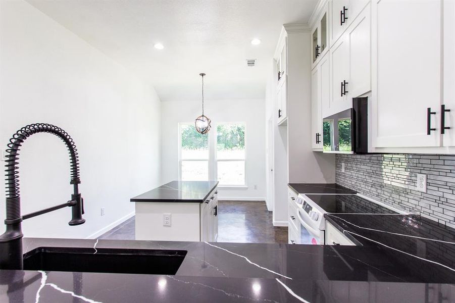 Kitchen featuring sink, white electric range oven, decorative light fixtures, decorative backsplash, and white cabinetry