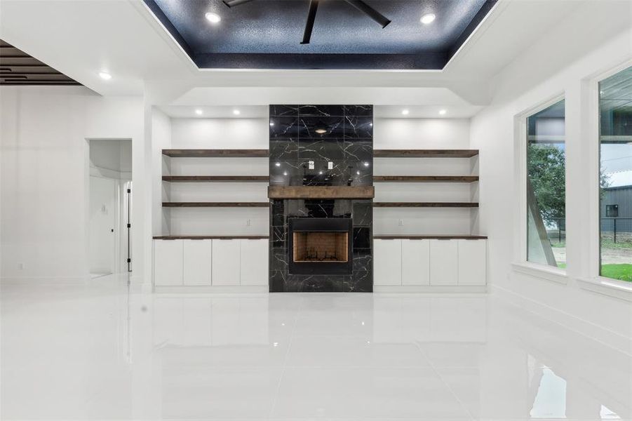 Unfurnished living room with a fireplace, tile patterned floors, and a raised ceiling