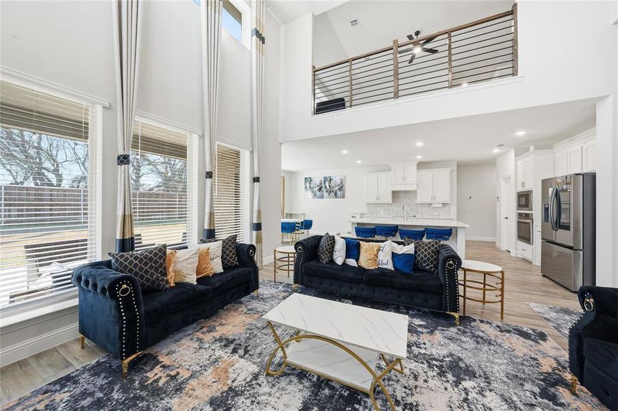 Living area featuring healthy amount of natural light, light wood-style flooring, a high ceiling, and recessed lighting