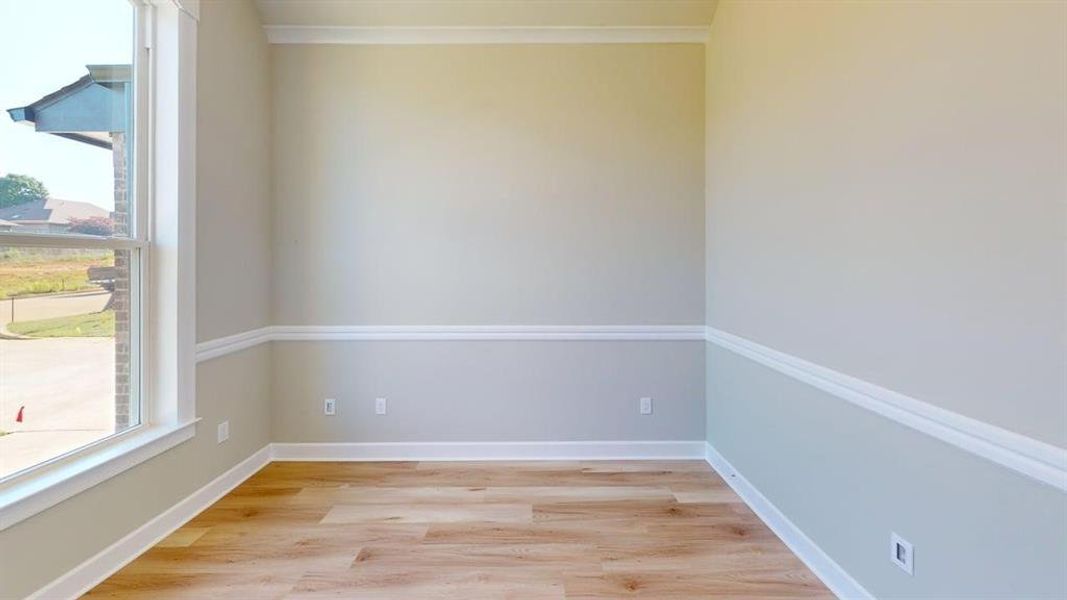 Empty room featuring light wood-style floors, crown molding, and baseboards