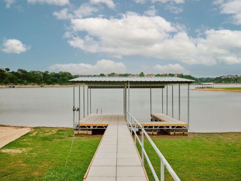 Covered boat dock featuring a metal roof, a wooden platform, and a white railing