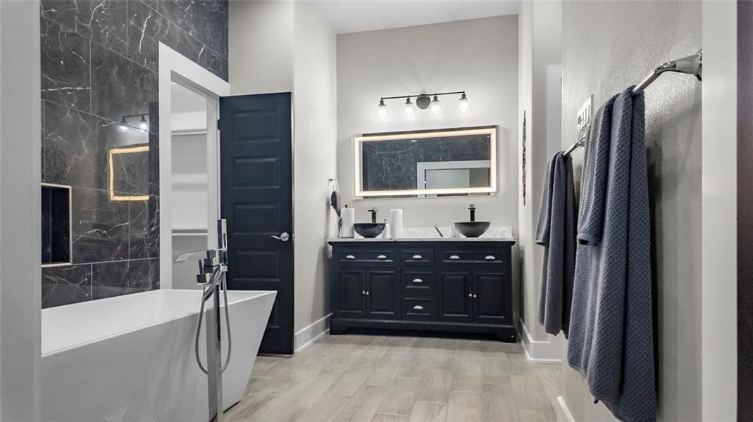 Bathroom featuring double vanity, a freestanding bath, and light wood finished floors