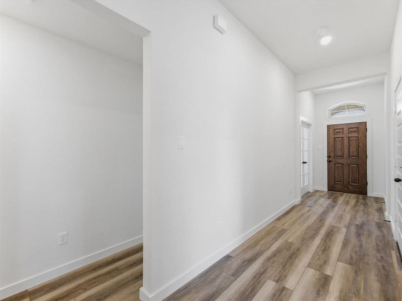 Foyer showcasing wood-finish flooring, white walls, and a front entry door with an arched transom window Foyer showcasing wood-finish flooring, white walls, and a front entry door with an arched transom window