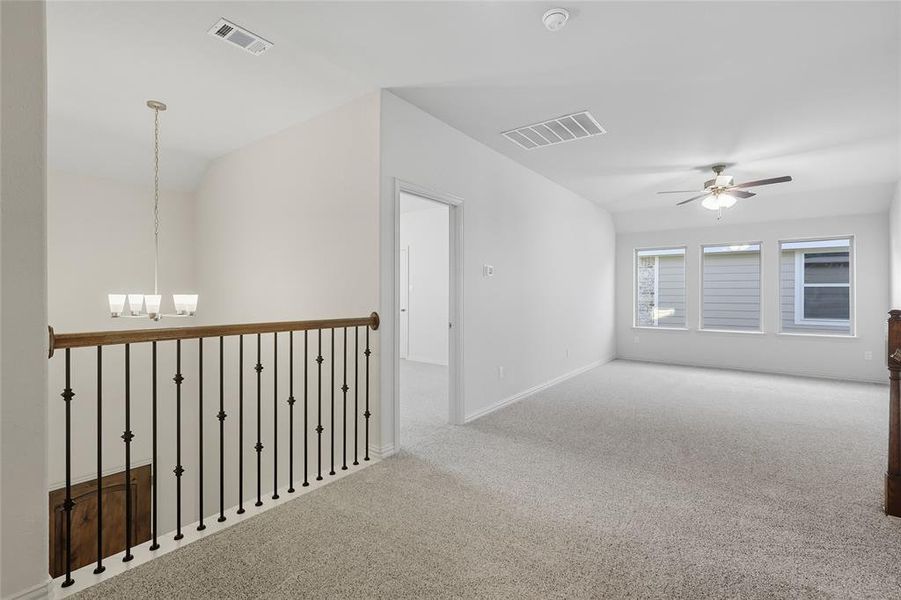 Corridor with carpet flooring, a chandelier, and lofted ceiling Corridor with carpet flooring, a chandelier, and lofted ceiling