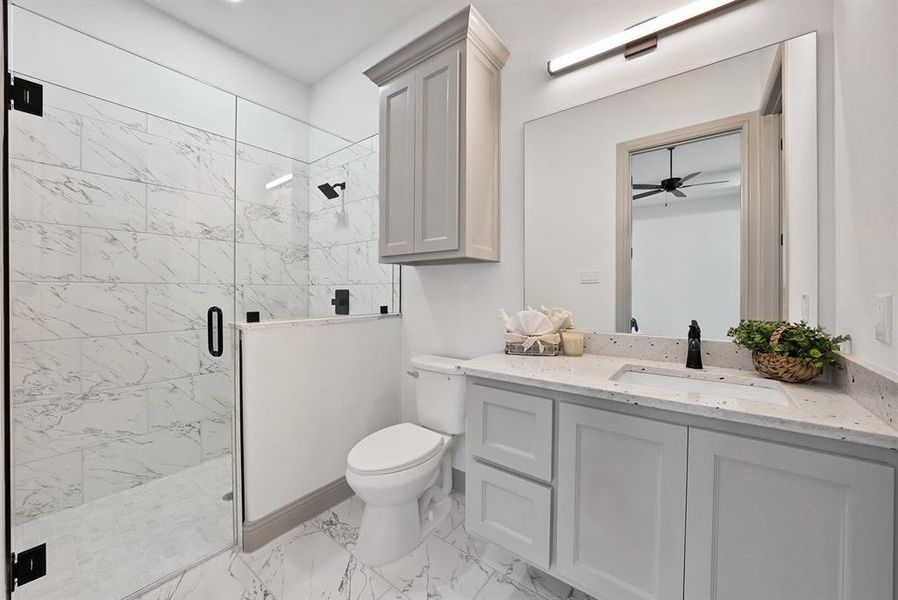 Full bath with a marble finish shower, vanity, light marble finish flooring, and a ceiling fan