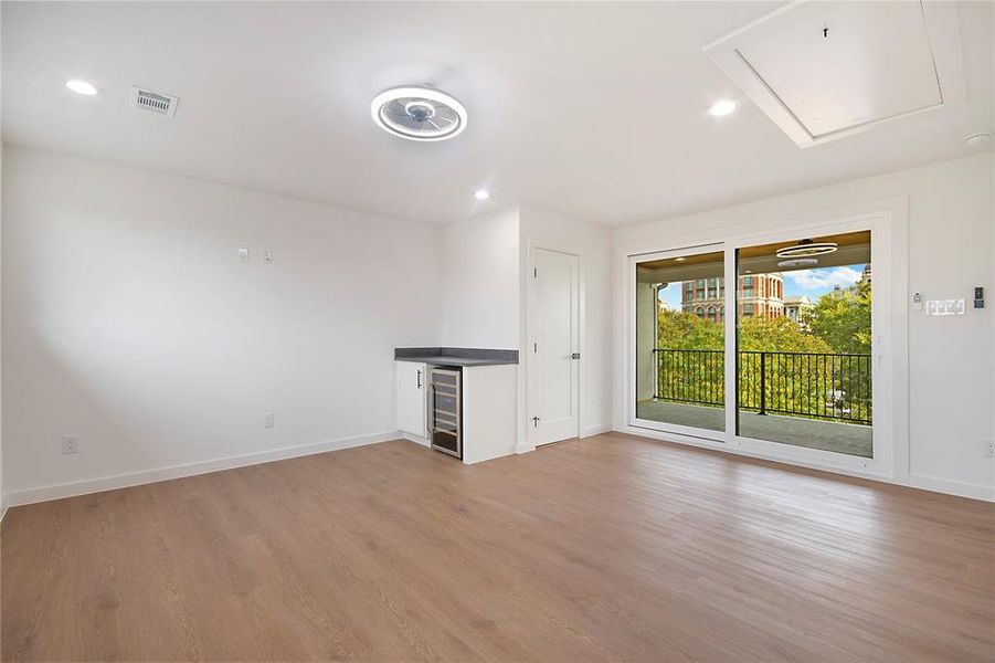 Unfurnished living room with light wood finished floors, recessed lighting, wine cooler, and attic access