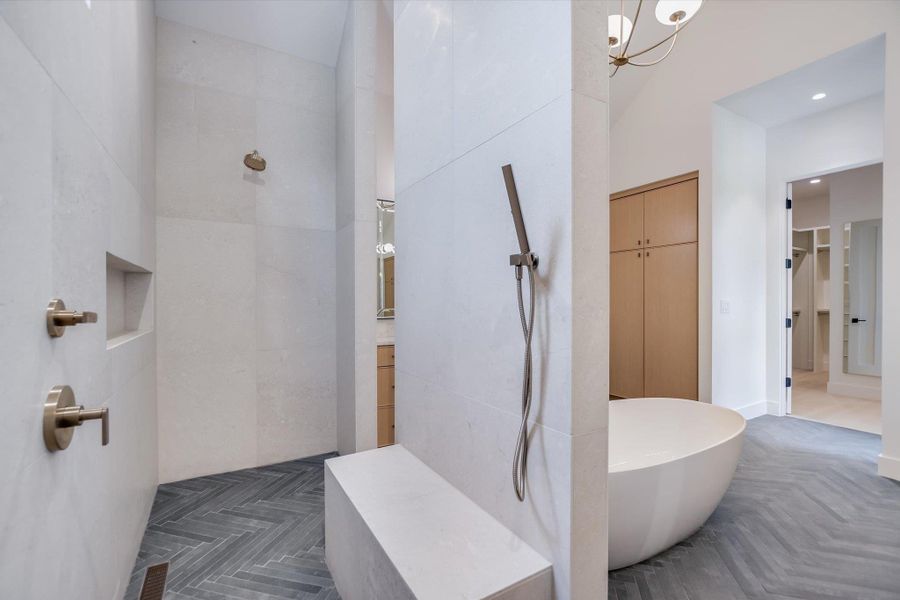 Indulge in this primary bathroom featuring a freestanding soaking tub and a spacious walk-in shower with a built-in bench.