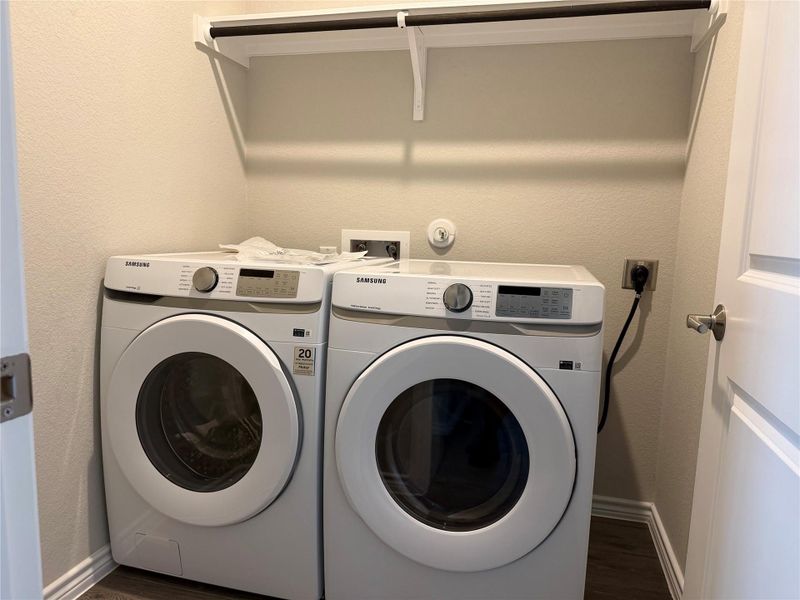 A dedicated laundry space offers convenience with a washer and dryer setup, complemented by a practical overhead shelf.