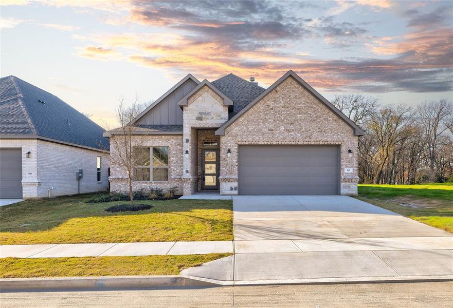 View of front of home with a garage and a yard