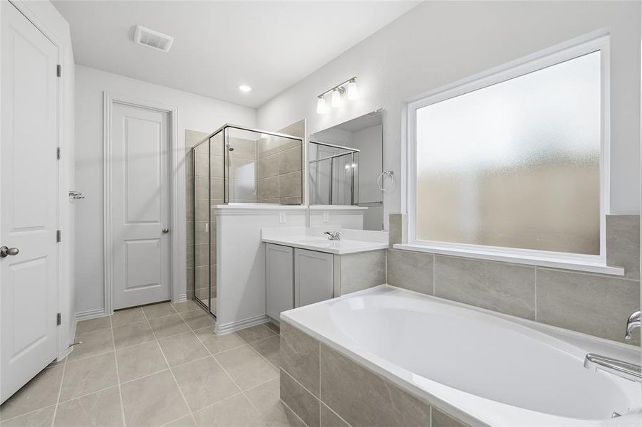 Bathroom with a garden tub, vanity, light tile patterned floors, and a shower stall