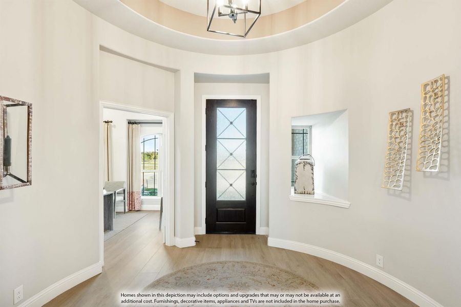Rounded foyer with tall ceilings, black front door with glass panels, and hardwood floors Rounded foyer with tall ceilings, black front door with glass panels, and hardwood floors