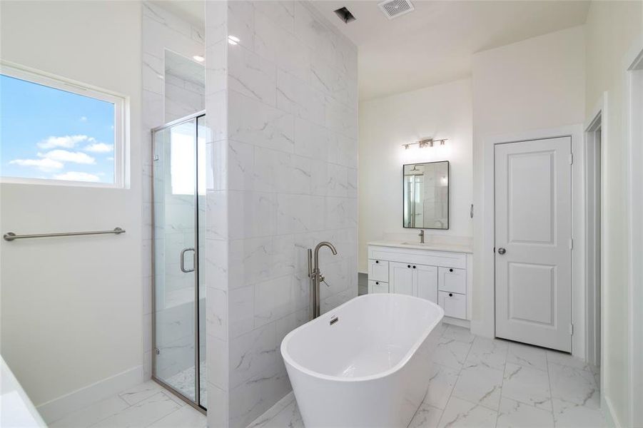 Bathroom featuring separate shower and tub and vanity