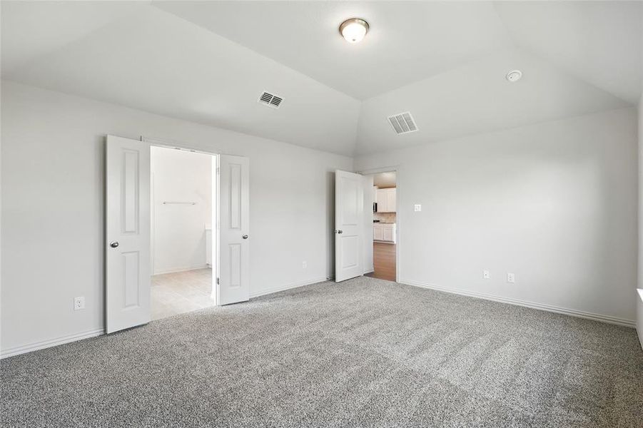 Unfurnished bedroom with lofted ceiling and light colored carpet Unfurnished bedroom with lofted ceiling and light colored carpet