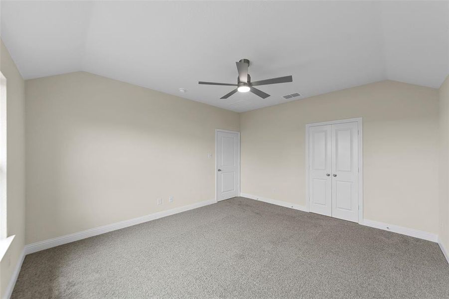 Carpeted room featuring a vaulted ceiling and a contemporary ceiling fan