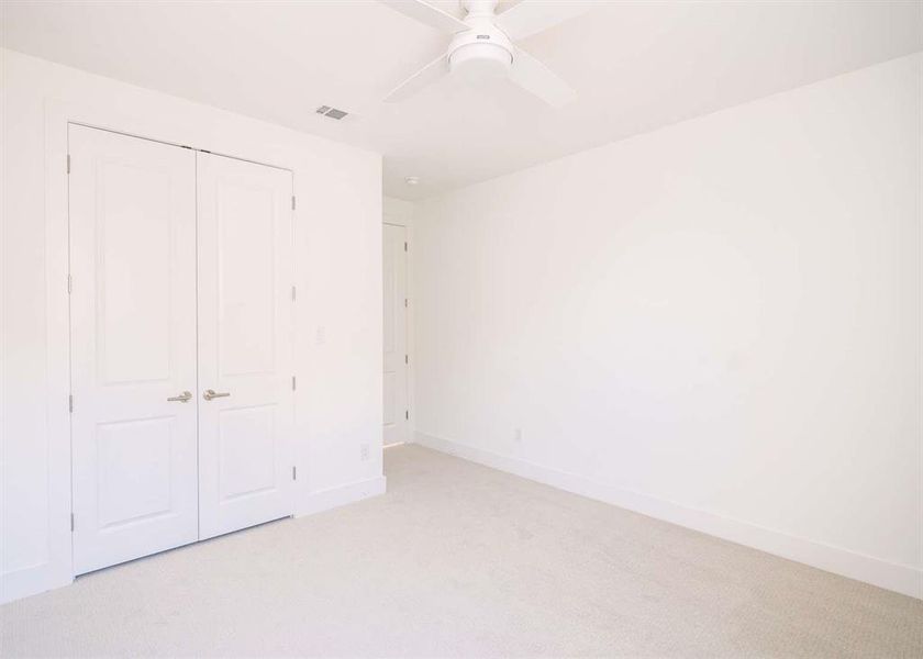 Unfurnished bedroom featuring ceiling fan, a closet, and light carpet