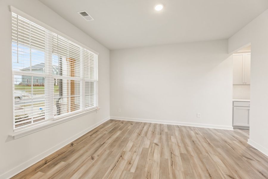 A room with a wood floor and a window with blinds. A room with a wood floor and a window with blinds.