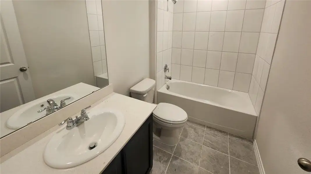 Bathroom featuring a white bathtub, ceramic tile shower surround, and a vanity with an integrated sink