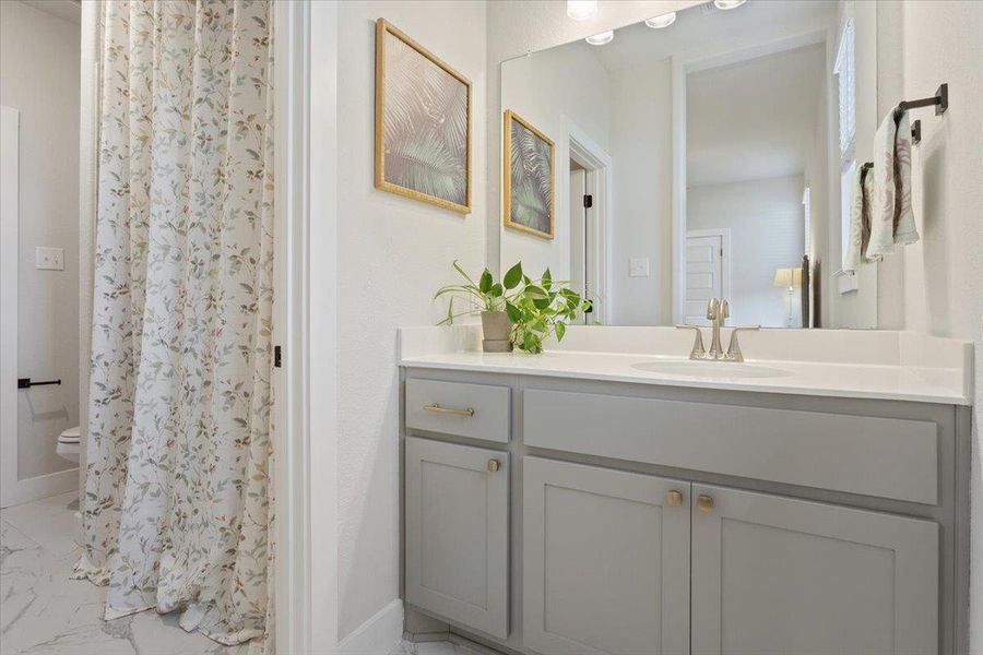 Full bathroom featuring vanity, light marble finish floors, and curtained shower
