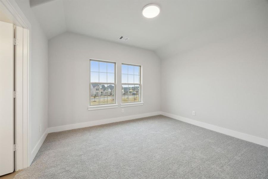 Carpeted empty room featuring lofted ceiling