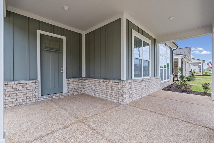 Entrance to property with board and batten siding, brick siding, and covered porch
