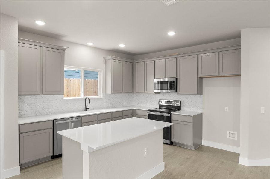 Kitchen with gray cabinets, appliances with stainless steel finishes, a sink, decorative backsplash, and recessed lighting Kitchen with gray cabinets, appliances with stainless steel finishes, a sink, decorative backsplash, and recessed lighting