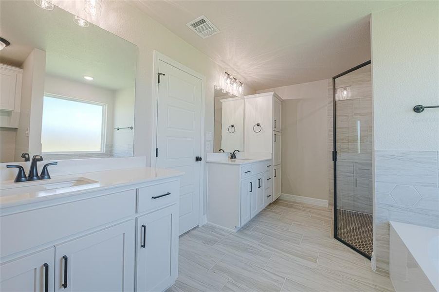 Full bathroom with two vanities, a bath, and a stall shower