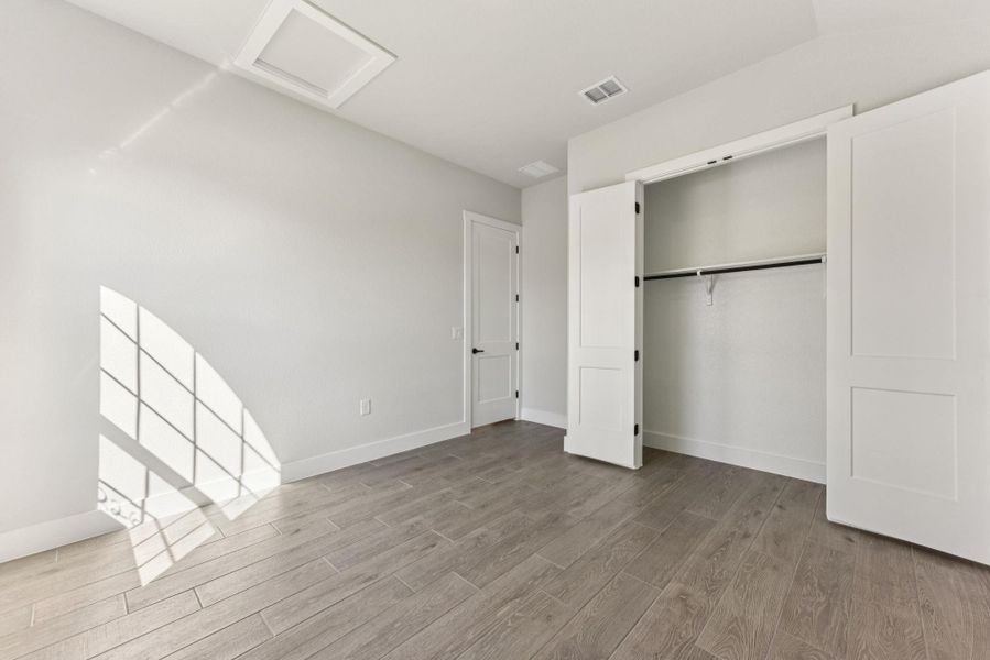 Unfurnished bedroom with attic access, light wood finished floors, and a closet Unfurnished bedroom with attic access, light wood finished floors, and a closet