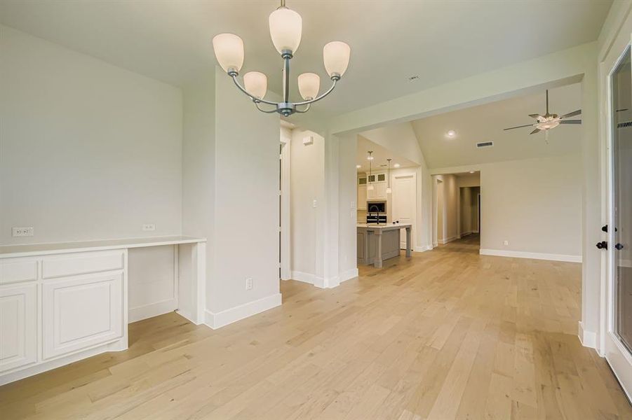 Unfurnished dining area with light wood-type flooring, a chandelier, and ceiling fan