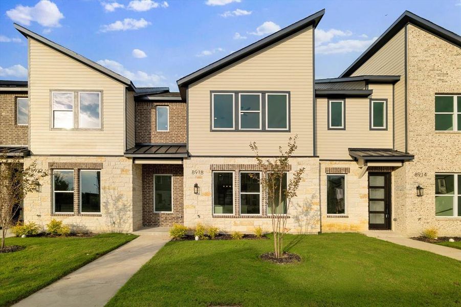 View of front of home with a standing seam roof, stone siding, a metal roof, and a front yard View of front of home with a standing seam roof, stone siding, a metal roof, and a front yard