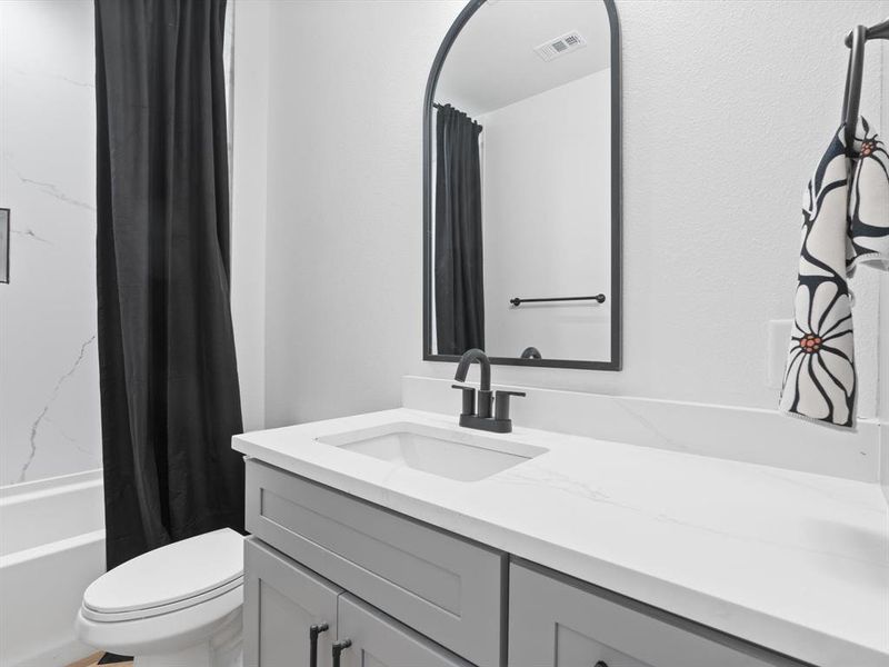 Full bathroom featuring vanity, shower / bath combo with shower curtain, visible vents, and toilet Full bathroom featuring vanity, shower / bath combo with shower curtain, visible vents, and toilet