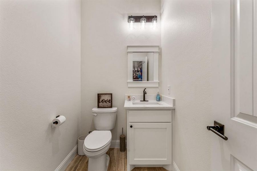 Bathroom featuring vanity, light wood-type flooring, and a textured wall Bathroom featuring vanity, light wood-type flooring, and a textured wall
