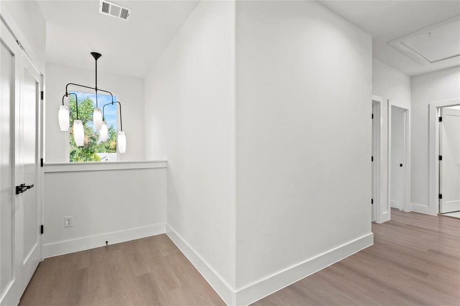 Corridor with wood finished floors and attic access