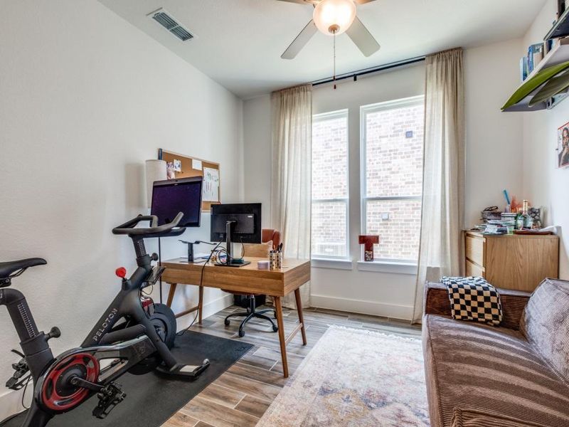 Home office with plenty of natural light, a ceiling fan, and wood finished floors