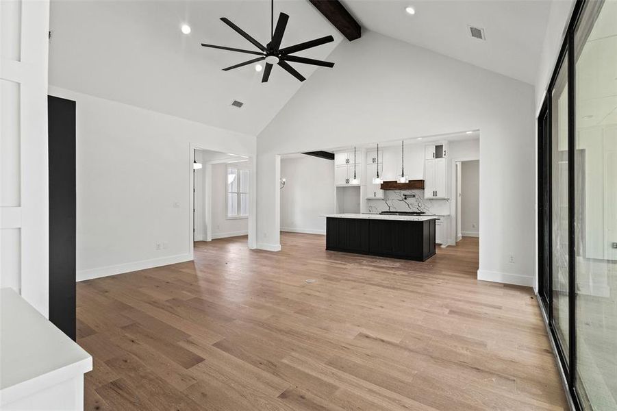 Unfurnished living room featuring a ceiling fan, beamed ceiling, high vaulted ceiling, light wood-style flooring, and recessed lighting Unfurnished living room featuring a ceiling fan, beamed ceiling, high vaulted ceiling, light wood-style flooring, and recessed lighting