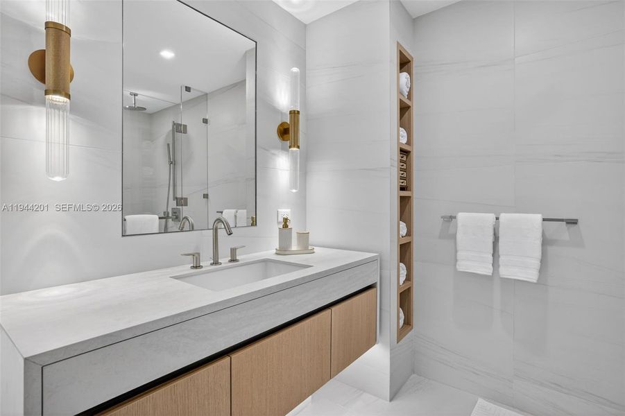 The 06 line primary bath feels like a private spa. Oversized and beautifully proportioned, it features a frameless glass walk in shower, designer soaking tub, dual vanities with stone counters, and sleek modern fixtures. Clean architectural lines, neutral luxury finishes, and generous storage for a calm, resort style retreat that complements the open coastal aesthetic of the residence.