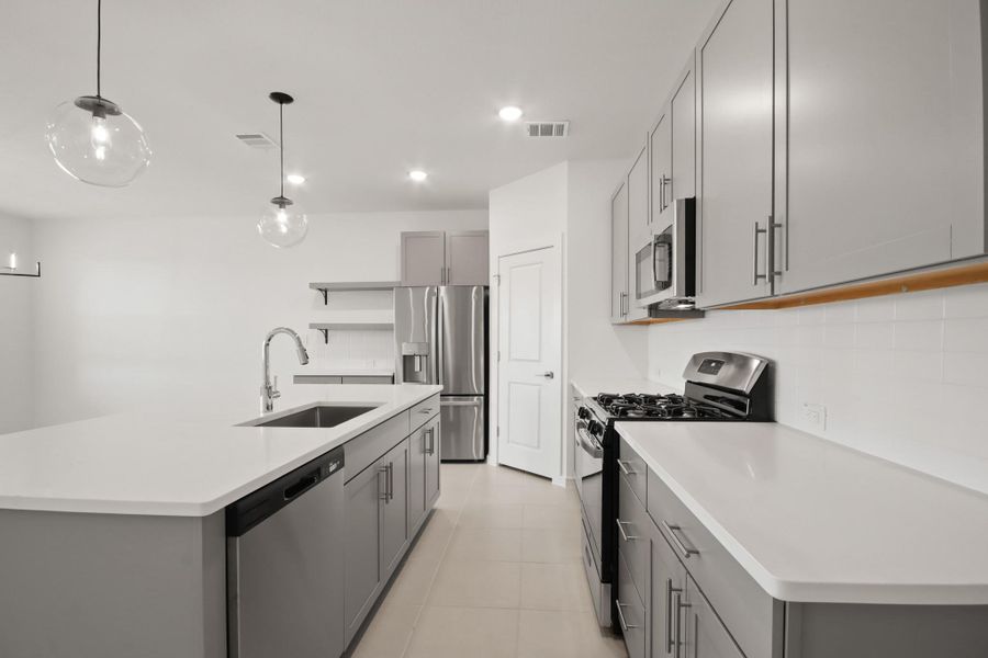 Stunning kitchen with light grey cabinets and quartz countertops