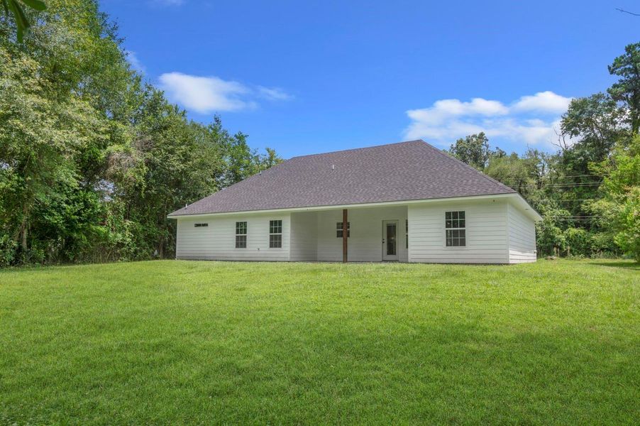 This photo showcases a single-story, white house with a sloped roof, set on a spacious, grassy lot surrounded by trees, offering a serene and private setting. This photo showcases a single-story, white house with a sloped roof, set on a spacious, grassy lot surrounded by trees, offering a serene and private setting.