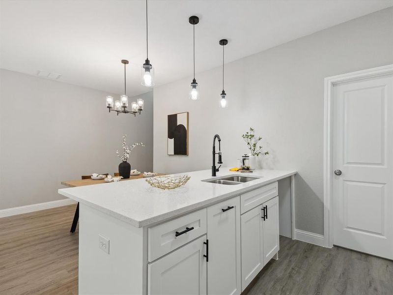 Kitchen with white cabinets, hanging light fixtures, hardwood / wood-style floors, a notable chandelier, and sink