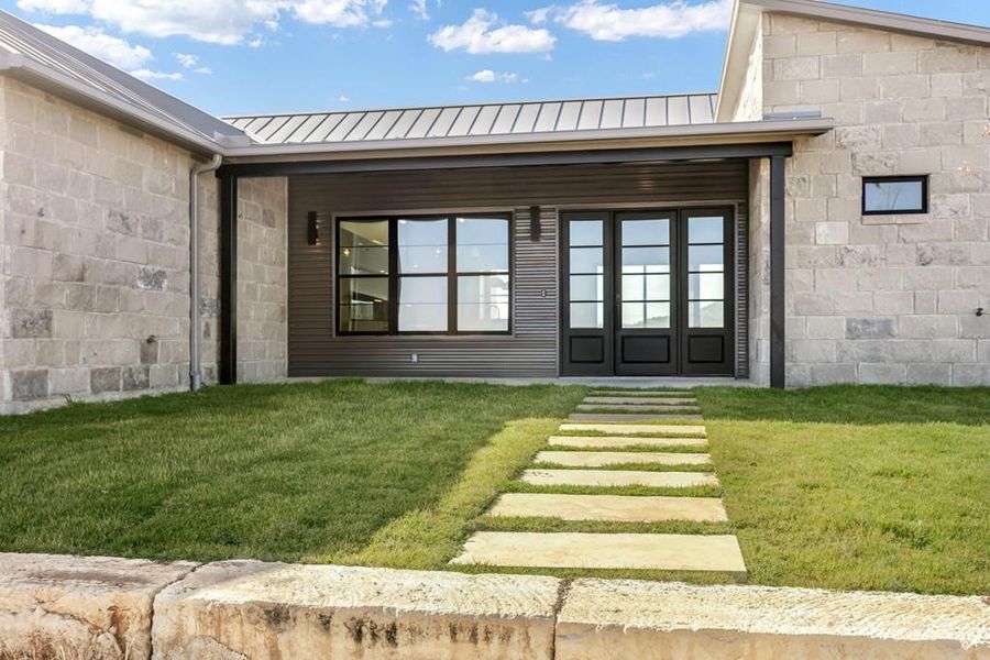 Entrance to property featuring a metal roof, a standing seam roof, and a yard Entrance to property featuring a metal roof, a standing seam roof, and a yard