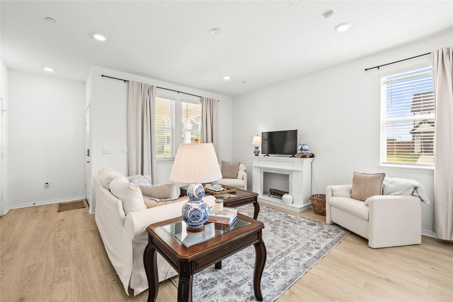 A well-lit living area showcases light wood flooring and a contemporary fireplace.