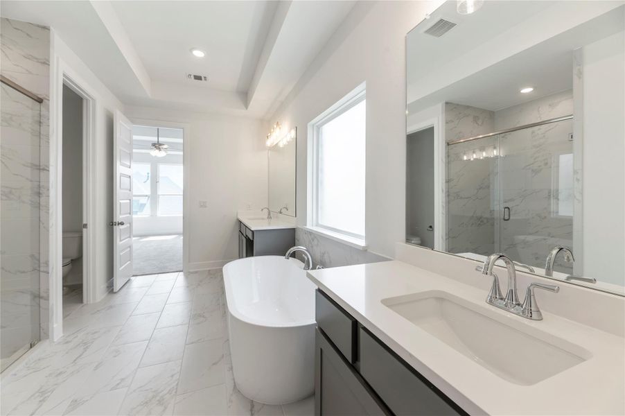 Full bath featuring light marble finish floors, vanity, a marble finish shower, a freestanding bath, and a ceiling fan Full bath featuring light marble finish floors, vanity, a marble finish shower, a freestanding bath, and a ceiling fan