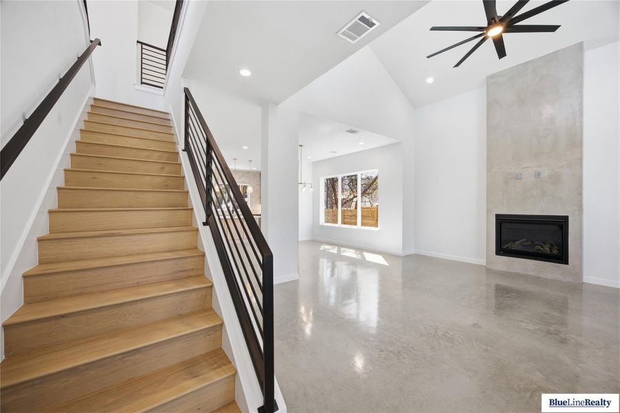 Stairs with a tile fireplace, a high ceiling, and a ceiling fan