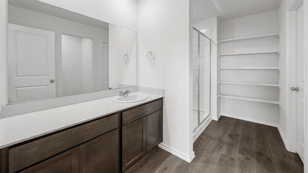 Contemporary bathroom featuring a single vanity with a white countertop and wood-finish cabinetry