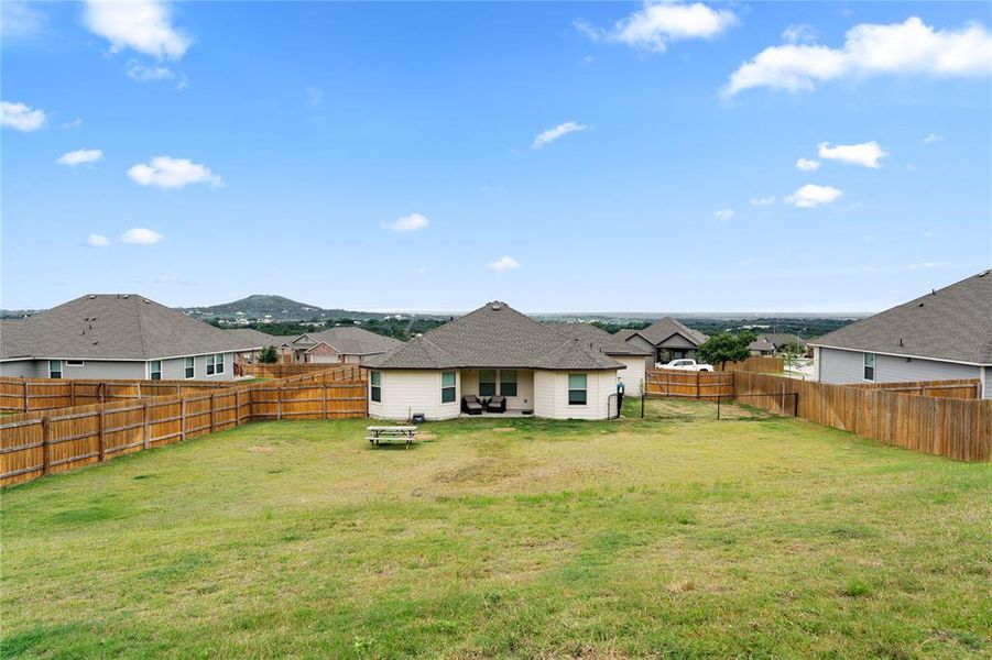Back of house with a patio area, a fenced backyard, a residential view, and roof with shingles