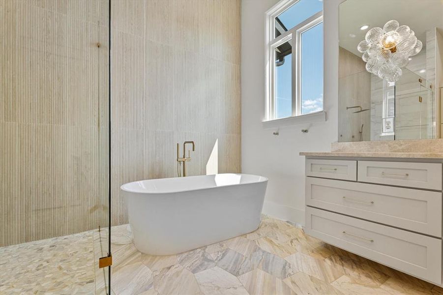 Bathroom with a freestanding tub, marble finish flooring, plenty of natural light, and vanity