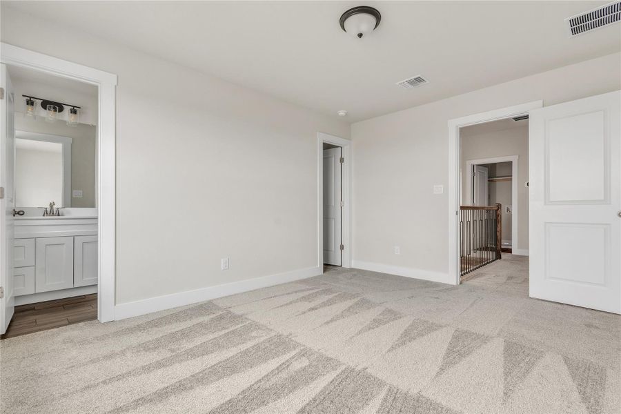 A spacious room offers comfortable carpeting, leading into an adjacent bathroom with a vanity and a nearby closet.