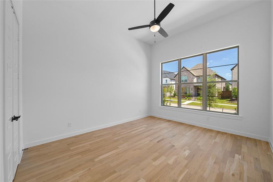 Spacious interior featuring light wood-finish flooring, vaulted ceilings, and a black ceiling fan