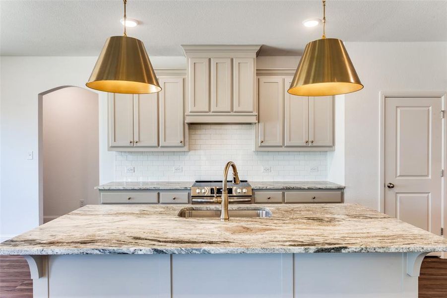 Kitchen with hanging light fixtures, dark hardwood / wood-style floors, sink, and backsplash