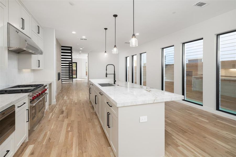 Kitchen with white cabinetry, a kitchen island with sink, and sink