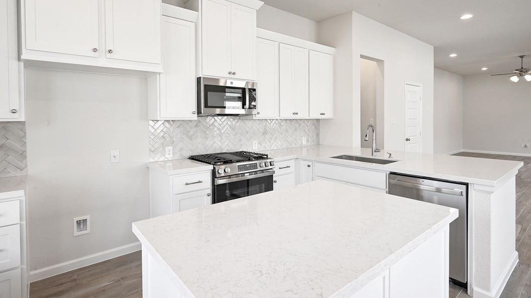 Kitchen featuring appliances with stainless steel finishes, tasteful backsplash, white cabinets, light wood-style flooring, and recessed lighting